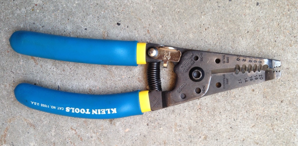 Klein Tools 11055 wire strippers with blue and yellow handles on concrete