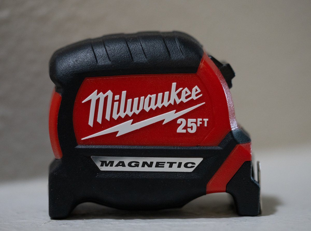 A red and black Milwaukee 25 ft compact tape measure with a silver "MAGNETIC" badge, seen from the side